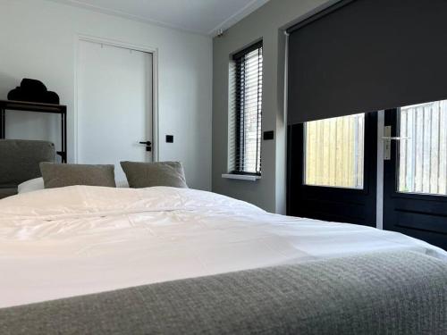 um quarto com uma grande cama branca e 2 janelas em Van Gogh Duplex Eindhoven-Nuenen em Nuenen