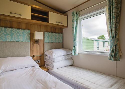 a bedroom with two beds and a window at Parc Farm Holiday Park in Mold