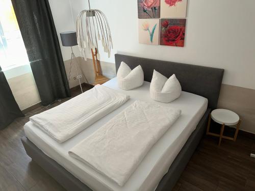 Elle comprend un grand lit avec des draps et des oreillers blancs. dans l'établissement Apartment Stabel 8,1 km von Europa Park, à Kippenheim