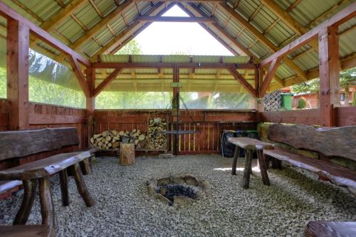 a wooden cabin with benches and a fire place at Domki Zacisze nad wodą in Baligród