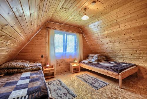sypialnia z 2 łóżkami w drewnianym domku w obiekcie Domki Zacisze nad wodą w Baligrodzie