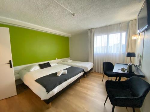 a bedroom with two beds and a green wall at Le Clos Du Pontic Logis et Cit'Hotel in Landerneau
