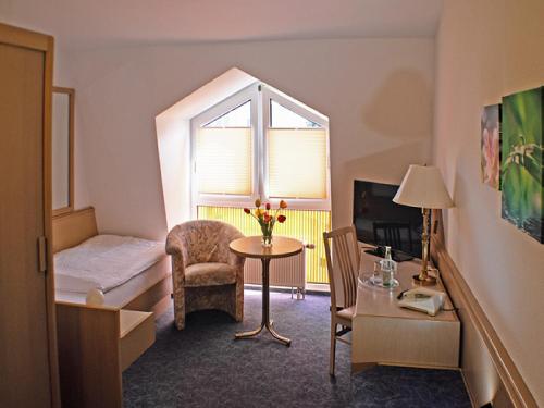 um quarto com uma cama, uma mesa e uma janela em Hotel Fürstenberg em Eisenhüttenstadt