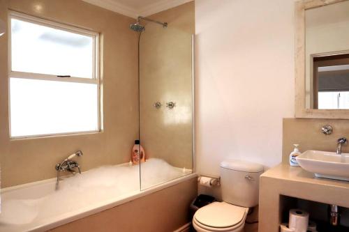 a bathroom with a tub and a toilet and a sink at Stylish house/Heated swimming pool-5min to Beach in Wilderness