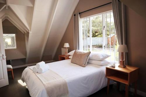 a bedroom with a large white bed with a window at Stylish house/Heated swimming pool-5min to Beach in Wilderness