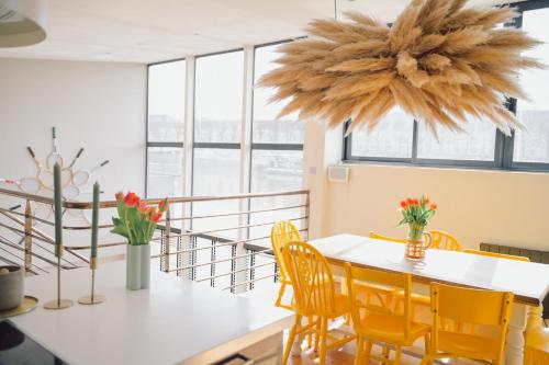 une salle à manger avec une table blanche et des chaises jaunes dans l'établissement Loft sur l'eau en centre-ville de Compiègne, à Margny-lès-Compiègne
