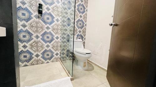 a bathroom with a toilet and blue and white tiles at Hotel MAYARI Holbox in Holbox Island