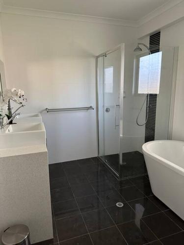 a bathroom with a shower and a tub and a sink at Seascape Beach House in Capel
