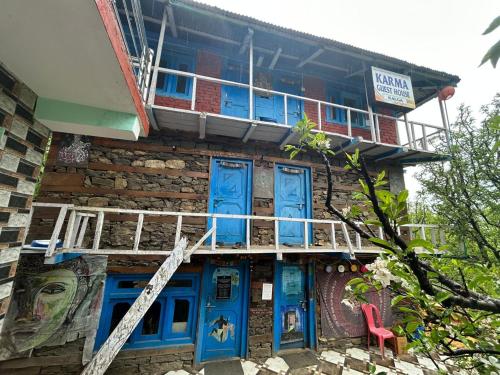 a building with blue doors and a balcony at Karma Guest House and Cafe in Kalgha