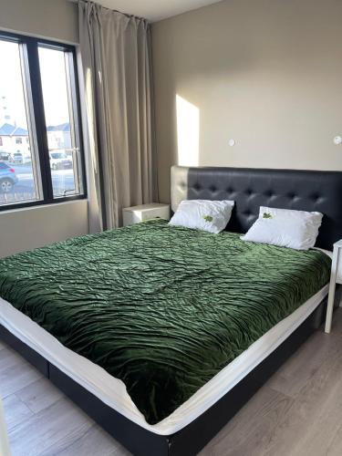a bed with a green comforter in a bedroom at Keflavik Apartments 101 in Keflavík