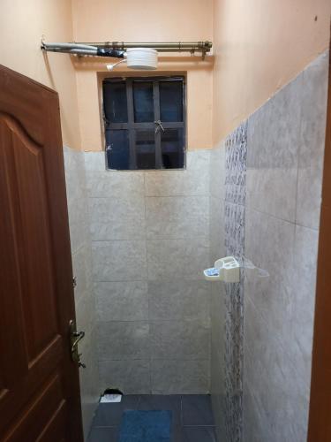 La salle de bains est pourvue d'une douche avec une porte en verre. dans l'établissement G&G Homes Naka Nakuru, à Nakuru
