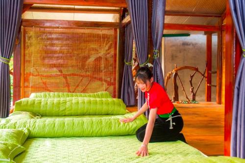 a young boy is playing on a green bed at Homestay Toan Tra Tram Tau in Cham Ta Lao