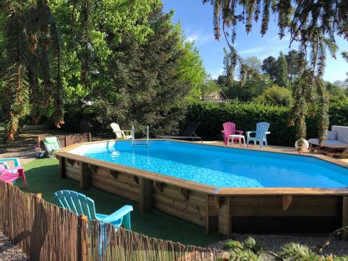 une grande piscine avec des chaises autour dans l'établissement Gites d'Ici et d'Ailleurs 1 & 2 -famille ou groupe- Dépendances dans propriété proche Bordeaux et Bassin Arcachon, à Saint-Morillon