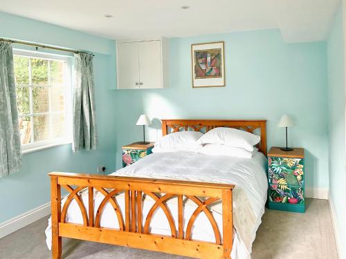 a bedroom with a wooden bed with blue walls at Garden Cottage 1 - Uk42881 in Liphook