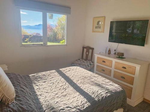 a bedroom with a bed and a dresser and a window at Casa La Quinta - Tiny House in San Carlos de Bariloche