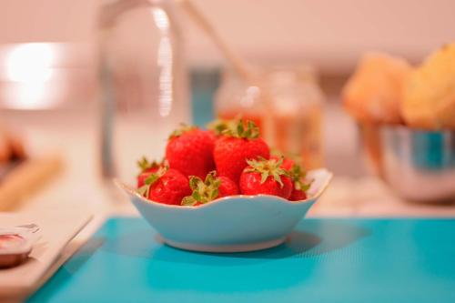 a bowl of strawberries sitting on a blue table at Il Cagliarese B&B in Cagliari