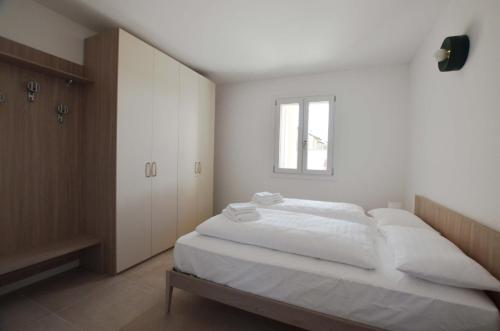 1 dormitorio con 1 cama con sábanas blancas y ventana en 51.b, en Aiello del Friuli