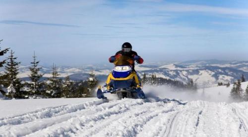 a person riding a snowmobile down a snow covered slope at Chalet 9029 Chemin des Alpages by Les Chalets Alpins in Stoneham