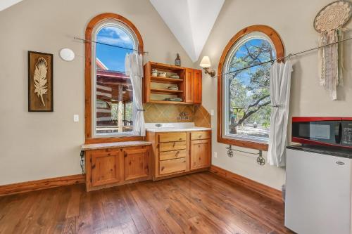 a kitchen with wooden cabinets and two windows at The Cabin at Rooster Ridge in Fischer