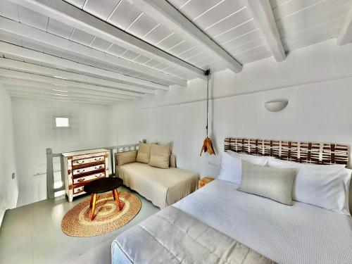 a bedroom with two beds and a chair in it at Sofos Suites Mykonos in Mikonos