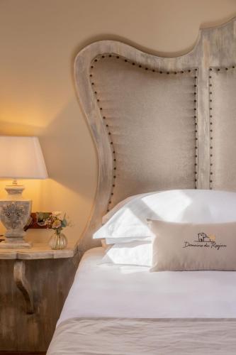 a bed with a wooden headboard and a table with a lamp at Domaine du Reginu in Santa-Reparata-di-Balagna
