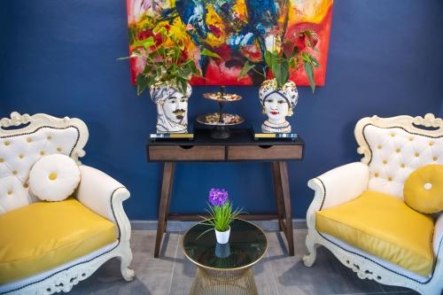 ein blaues Zimmer mit 2 Stühlen und einem Tisch mit Blumen in der Unterkunft Boutique Hotel Ferrara in Ferrara