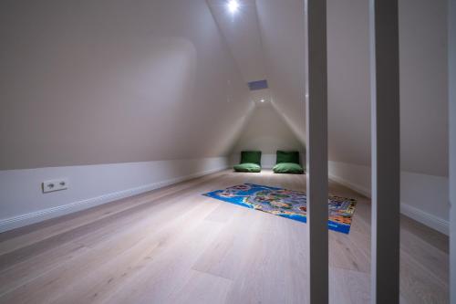 a room with white walls and wooden floors and green pillows at Frigga in Nieblum