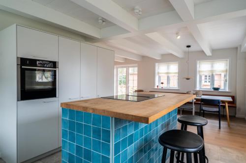 a kitchen with blue tiles on the counter and stools at Frigga in Nieblum
