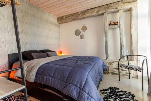 Schlafzimmer mit einem Bett mit blauer Decke in der Unterkunft Le grand clos, 3 étoiles in Pont-Saint-Martin