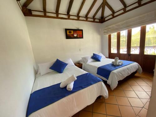 a bedroom with two beds with blue and white sheets at Hotel Casa Campestre Villa Anita in Villa de Leyva