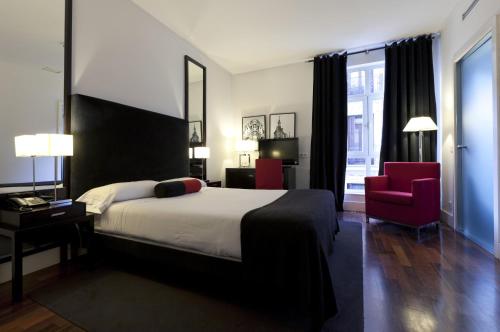 um quarto com uma cama grande e uma cadeira vermelha em Quatro Puerta del Sol em Madrid