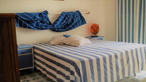 a bedroom with a blue and white striped bed with two pillows at MareDentro in Mazara del Vallo