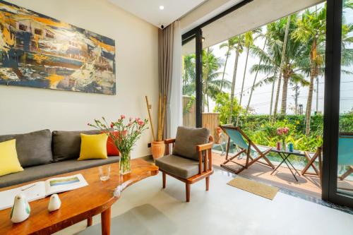 a living room with a couch and a table and chairs at Saca Townhouse by Class6 in Hoi An