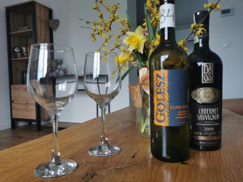 a bottle of wine and two wine glasses on a table at Zielony Zakątek Ciężkowice in Ciężkowice