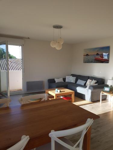 un salon avec une table et un canapé dans l'établissement Au cœur du Bassin d'Arcachon, à Gujan-Mestras