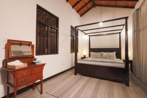 1 dormitorio con cama, tocador y espejo en Balumgala Estate Bungalow Kandy, 