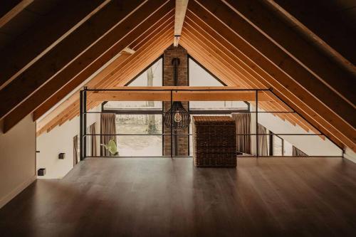 an attic room with a large window and a staircase at Luxe schuurwoning 't Nieuwt in Chaam, Nederland in Chaam