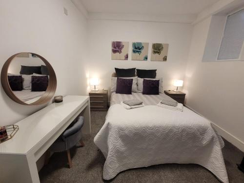 a white bedroom with a bed and a mirror at La Casa Bella in Sheffield