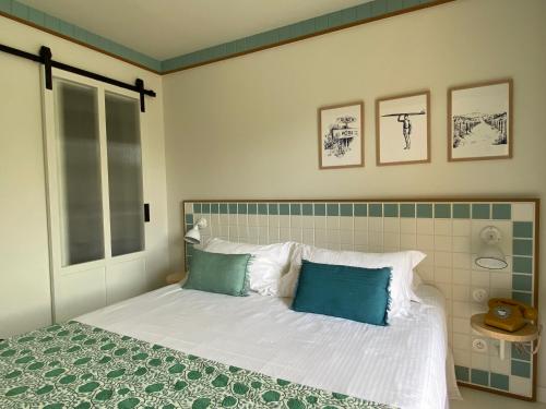 a bedroom with a bed with white sheets and blue pillows at Hotel des Dunes in Cap-Ferret