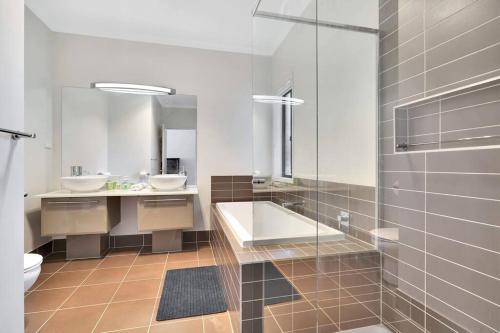 een badkamer met 2 wastafels, een bad en een toilet bij Spacious 4BR House In Great Location in Point Cook