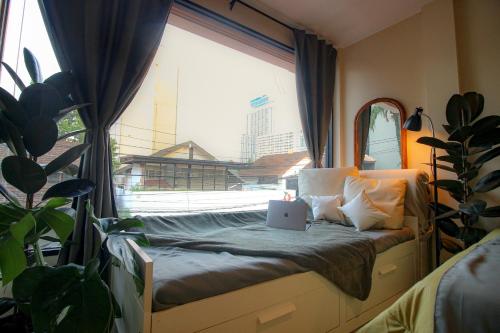 a bed in a room with a window with a laptop on it at Napshot Guesthouse in Bangkok