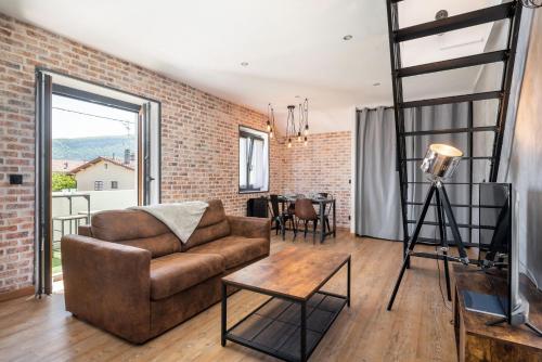 a living room with a couch and a brick wall at Superbe Loft industriel - Casa Vostra - CAUTION 800 EUR & ID requises - Gaillard Tram-Frontière in Gaillard