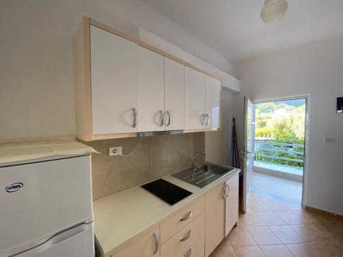 una cocina con armarios blancos y fregadero en Wave n' Sea Apartments en Himare