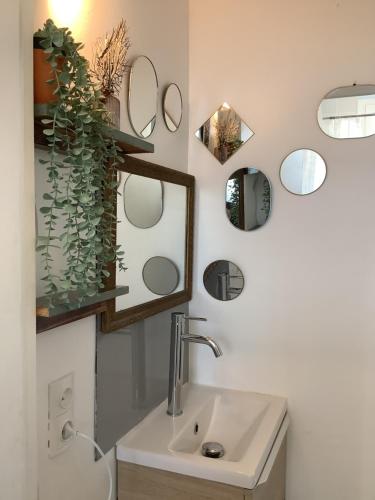 a bathroom with a sink and mirrors on the wall at Rue des roses in Saint-Pierre-dʼOléron