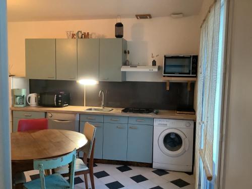 - une cuisine avec une table et un lave-linge dans l'établissement Rue des roses, à Saint-Pierre-dʼOléron