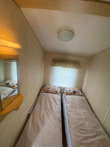 a small room with two beds and a mirror at Annie’s Corner in Ingoldmells