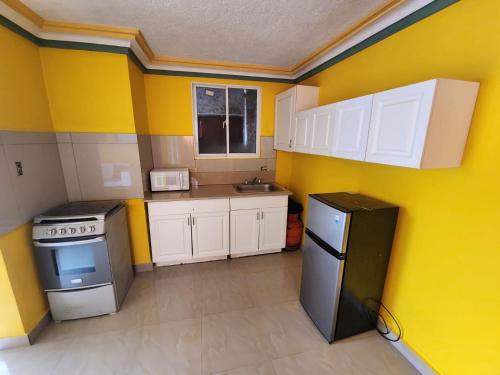 Elle comprend une petite cuisine avec des murs jaunes et des placards blancs. dans l'établissement Super Two Bedroom Penthouse in Peguy-Ville, 