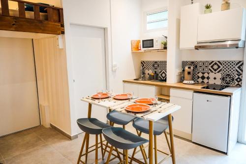 a kitchen with a table and stools in a room at Le Sunset, Magnifique Studio pieds dans l'eau, L'Ermitage les Bains in Filaos