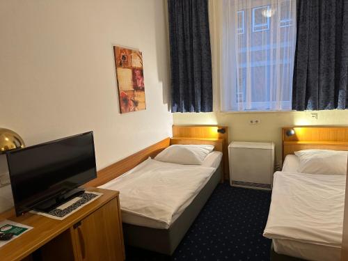 a hotel room with two beds and a flat screen tv at Centrum Hotel Commerz am Bahnhof Altona in Hamburg