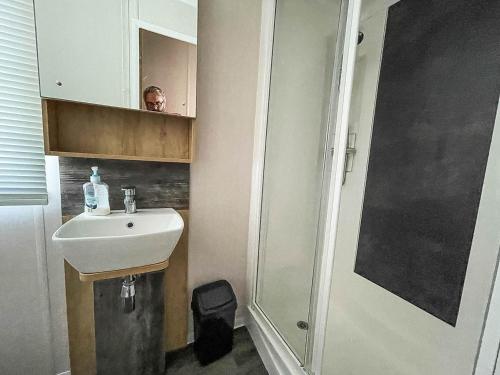 een badkamer met een wastafel en een douche met een persoon in de spiegel bij Beautiful Caravan With Decking At Naze Marine Park, Sleeps 8 Ref 17341br in Walton-on-the-Naze